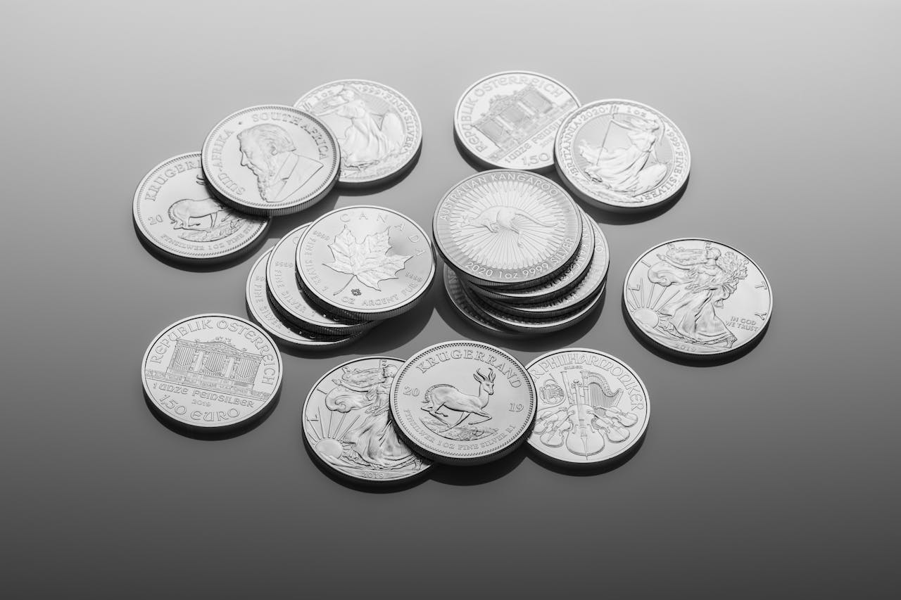 A close-up of various silver bullion coins, showcasing intricate designs on a reflective surface.